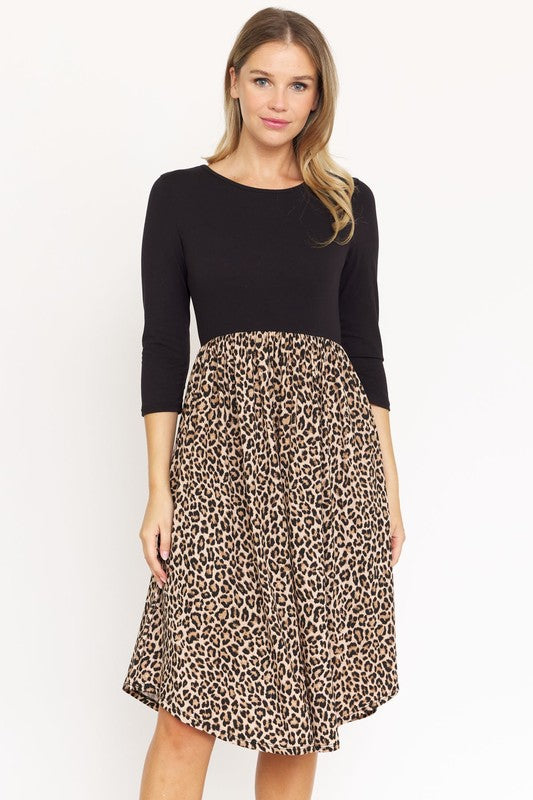 A woman in a fashionable Quarter Sleeve Midi Dress poses against a plain background, showcasing its elegant leopard print.