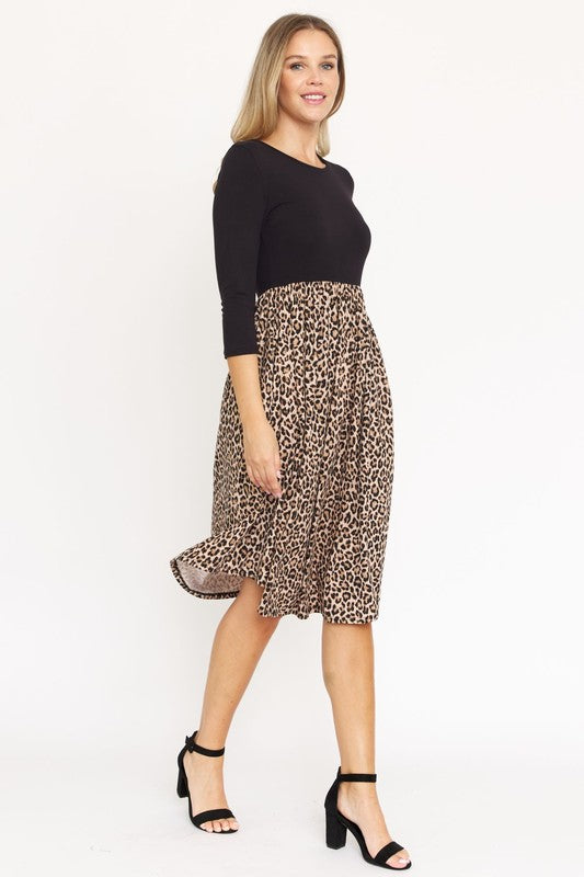 A woman in a fashionable Quarter Sleeve Midi Dress poses against a plain background, showcasing its elegant leopard print.