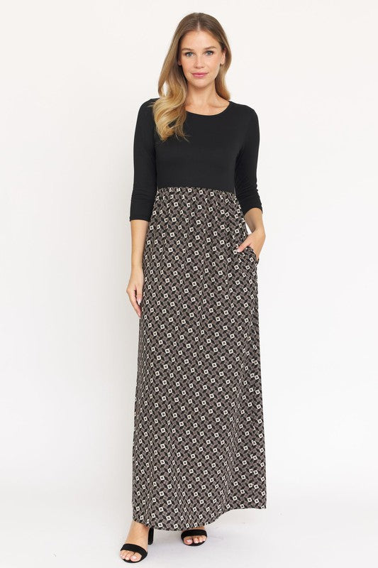 A woman with blonde hair elegantly models a Quarter Sleeve Maxi Dress, featuring intricate patterns and crafted in the United States, against a plain white background.