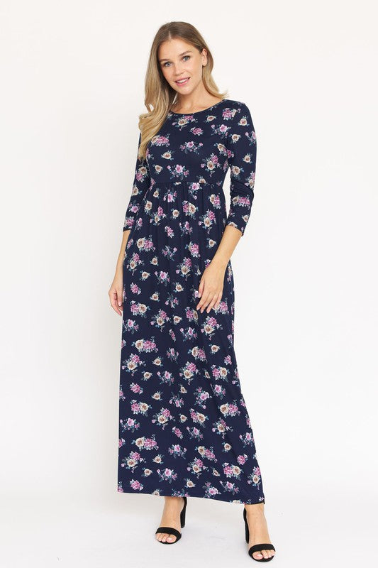 A woman stands wearing a dark blue Plus Bouquet Floral Quarter Sleeve Maxi Dress with black heels, against a plain white background.