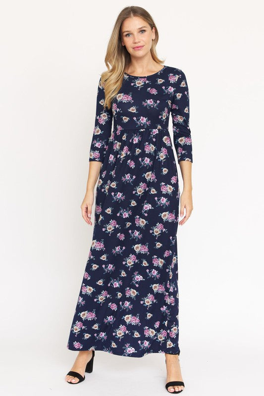 A woman stands wearing a dark blue Plus Bouquet Floral Quarter Sleeve Maxi Dress with black heels, against a plain white background.