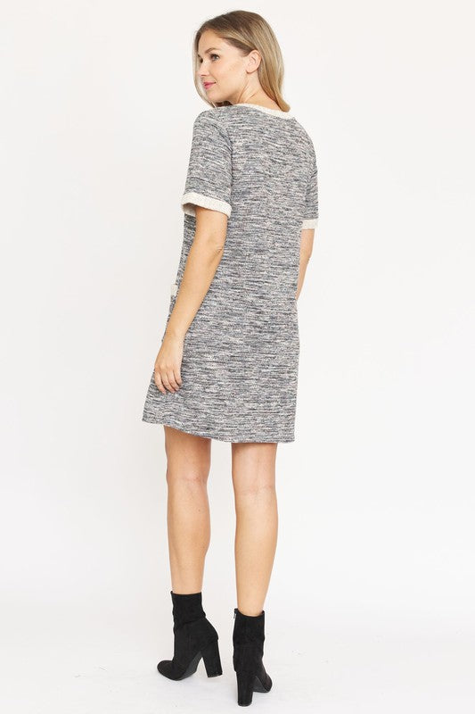 A woman with long blonde hair models the short-sleeved Preppy Tweed Shift Dress in gray and white, featuring two front pockets. She stands against a plain white background, smiling at the camera.