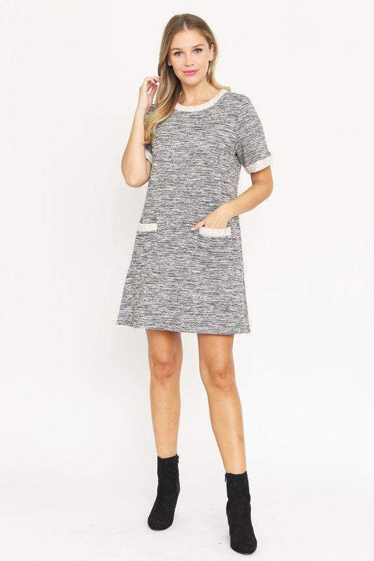 A woman with long blonde hair models the short-sleeved Preppy Tweed Shift Dress in gray and white, featuring two front pockets. She stands against a plain white background, smiling at the camera.