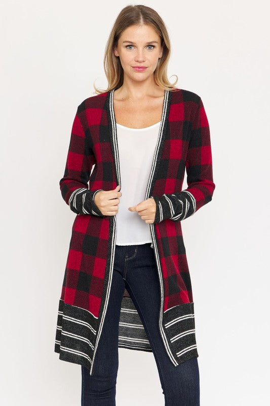 A woman is wearing a Long Buffalo Plaid Stripe Trim Open Cardigan over a white top and dark jeans, standing against a plain background.