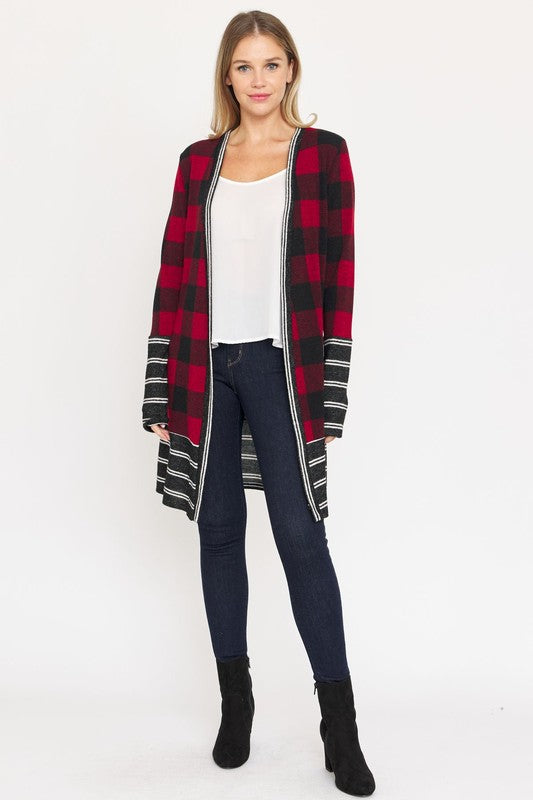 A woman is wearing a Long Buffalo Plaid Stripe Trim Open Cardigan over a white top and dark jeans, standing against a plain background.