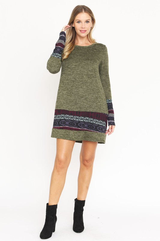 A woman in a maroon Nordic Print Knit Dress, featuring intricate patterned bands at the hem and cuffs, smiles at the camera against a plain white background.