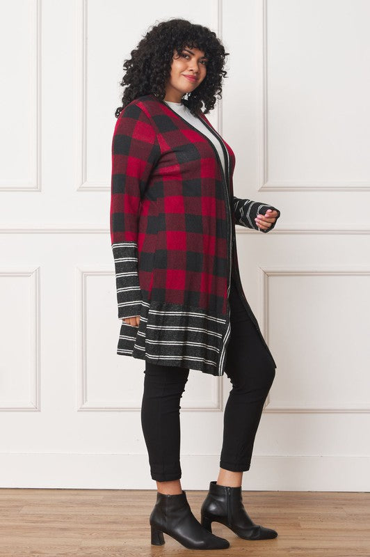 A person with curly hair is wearing a Long Buffalo Plaid Stripe Trim Open Cardigan in black and white over a white shirt, paired with black high-waisted pants with buttons. They stand in front of a white paneled wall.