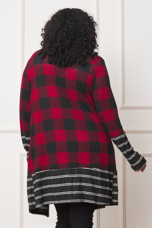 A person with curly hair is wearing a Long Buffalo Plaid Stripe Trim Open Cardigan in black and white over a white shirt, paired with black high-waisted pants with buttons. They stand in front of a white paneled wall.