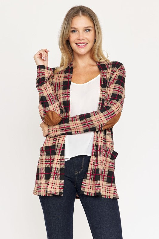 A woman with curly hair is standing against a white background, wearing a white shirt, black pants, and a Plaid Contrast Elbow Patch Cardigan made in the United States.