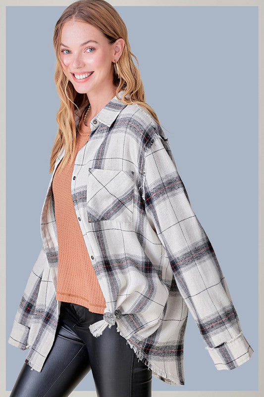 A person with long blonde hair wearing a black cap and an oversized Celine Shirt, which features a blue checkered plaid flannel design, showing a slight smile against a neutral background.