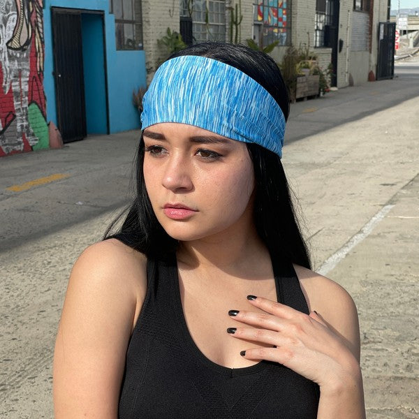 Woman with an Extra-Wide Sport Headband against a blue wall.