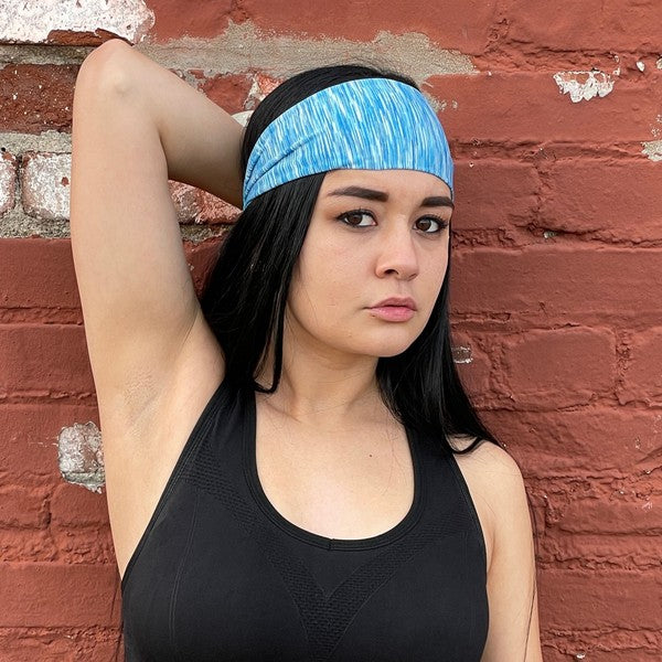 Woman with an Extra-Wide Sport Headband against a blue wall.