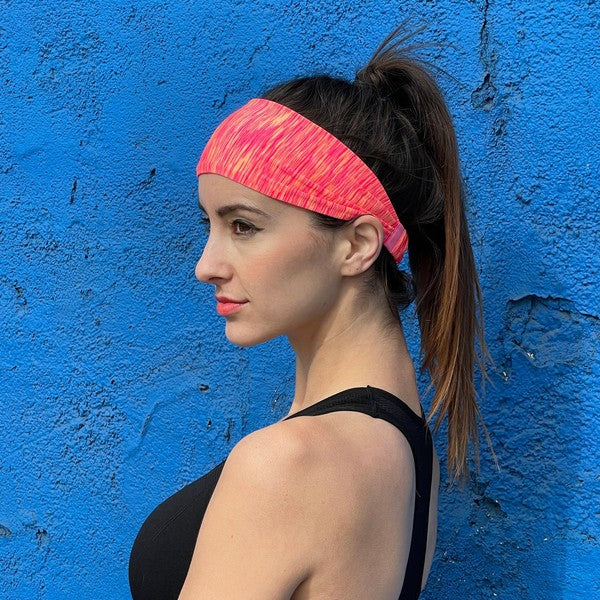 Woman with an Extra-Wide Sport Headband against a blue wall.