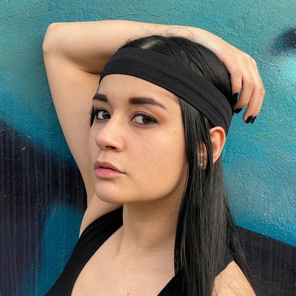 Woman with Running Sweat-Wicking Headband against a black brick wall.