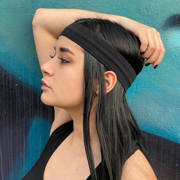 Woman with Running Sweat-Wicking Headband against a black brick wall.