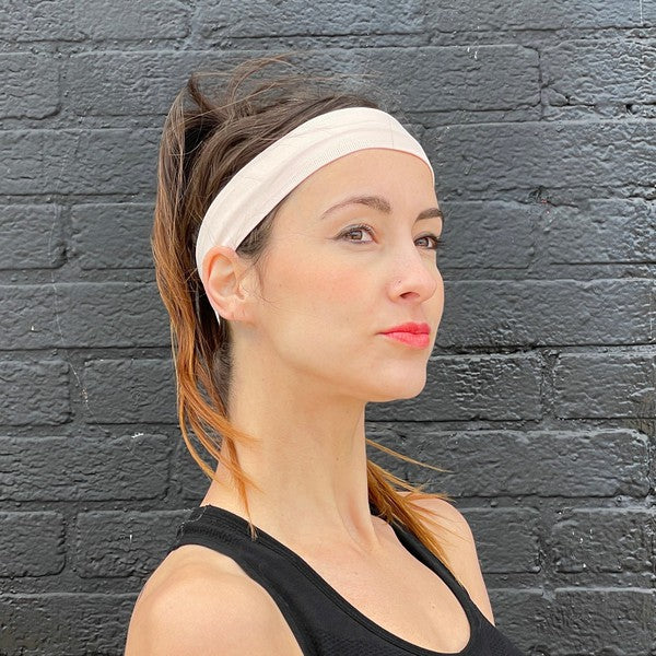 Woman with Running Sweat-Wicking Headband against a black brick wall.