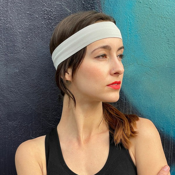 Woman with Running Sweat-Wicking Headband against a black brick wall.