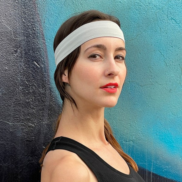 Woman with Running Sweat-Wicking Headband against a black brick wall.