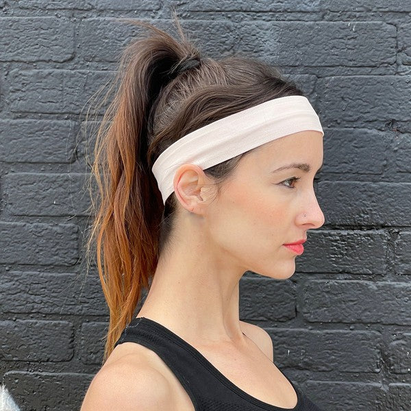Woman with Running Sweat-Wicking Headband against a black brick wall.