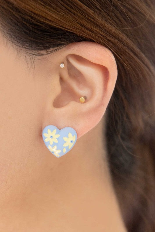 A diagonal line of Flower Lover Stud Earrings with floral patterns on a white background, featuring yellow stud hearts with Sterling Silver Posts.