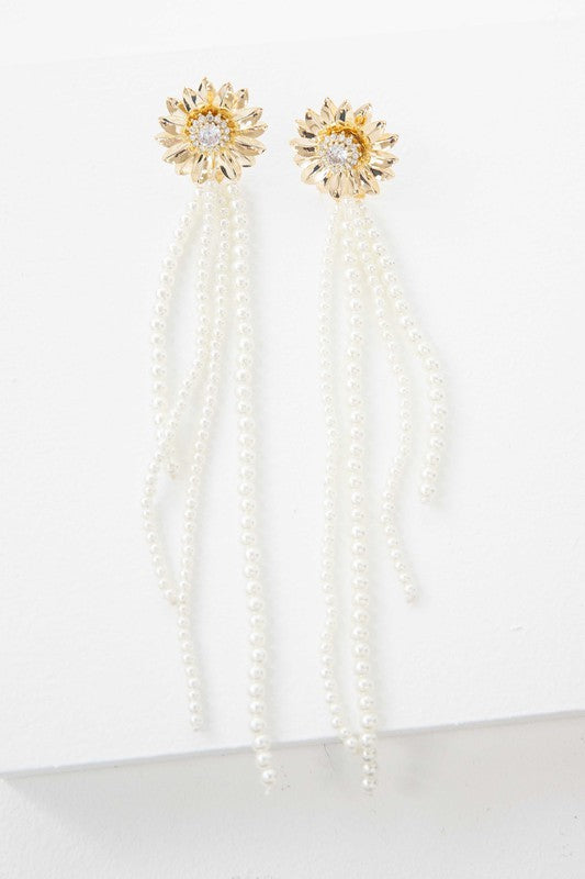 A pair of Dandelion Pearl Drop Earrings with pearl tassels against a white background, featuring 14k gold plating.