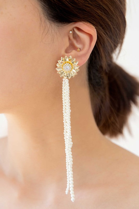 A pair of Dandelion Pearl Drop Earrings with pearl tassels against a white background, featuring 14k gold plating.
