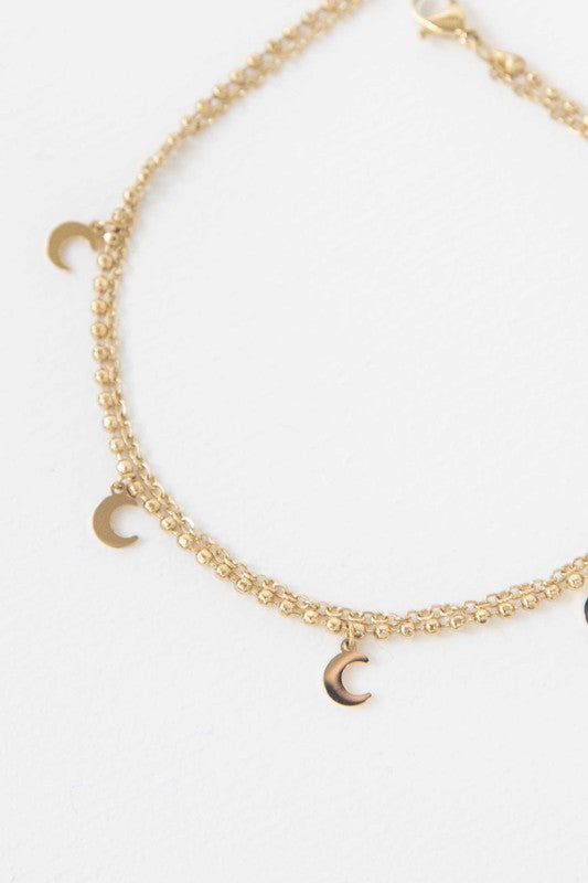 Sentence with Product Name: La Lune Anklet with double-layered crescent moon charms against a white background.