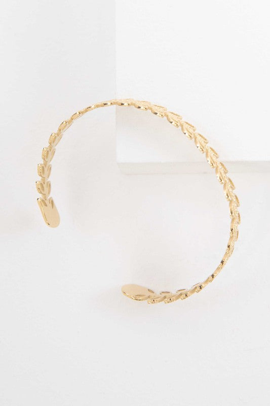 Fern cuff bracelet with 14k gold plating on a white background.
