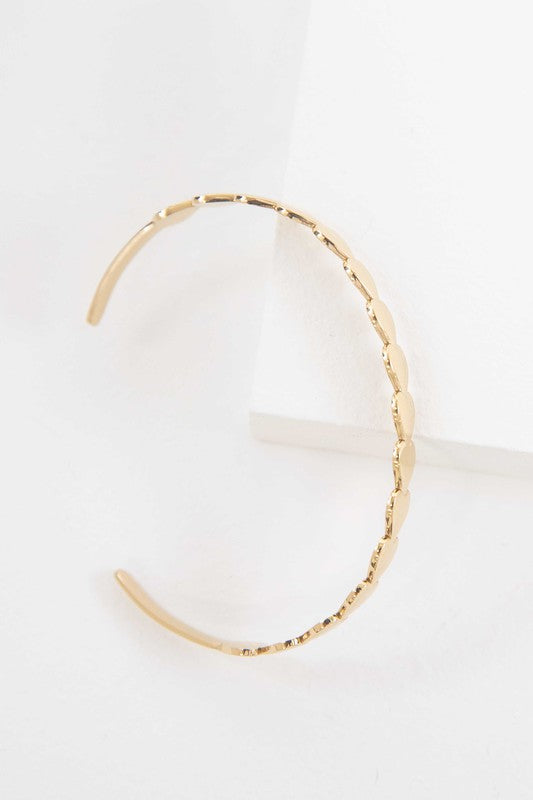 Two Spades cuff bracelets with leaf designs, one in 14k gold plating and one in stainless steel, against a white background.