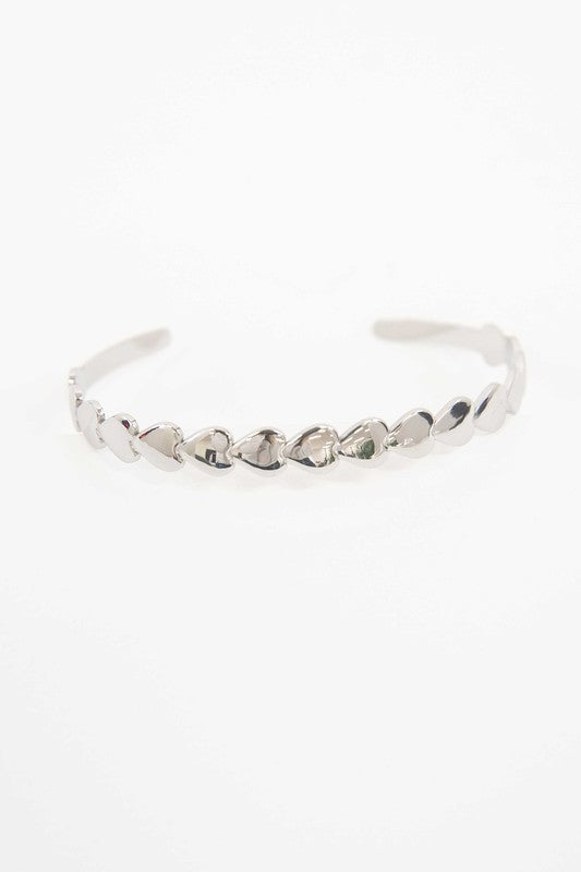 Two Spades cuff bracelets with leaf designs, one in 14k gold plating and one in stainless steel, against a white background.