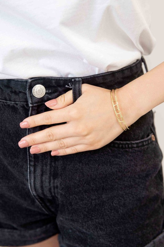 Two Wired Cuff Bracelets, one silver-toned stainless steel and one gold-plated, with gemstone embellishments, displayed against a white background.