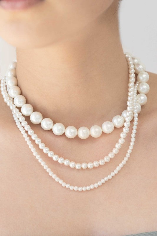 Layered pearl necklace on a white background.
