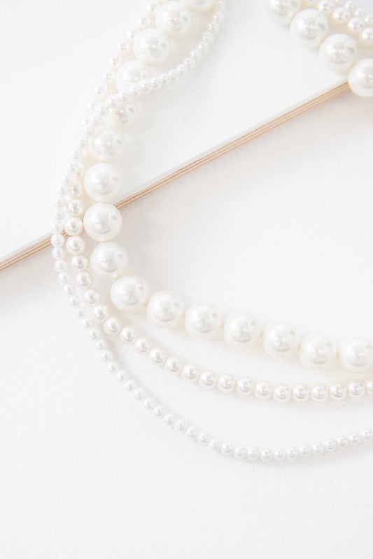 Layered pearl necklace on a white background.