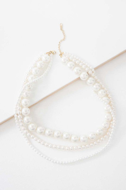 Layered pearl necklace on a white background.