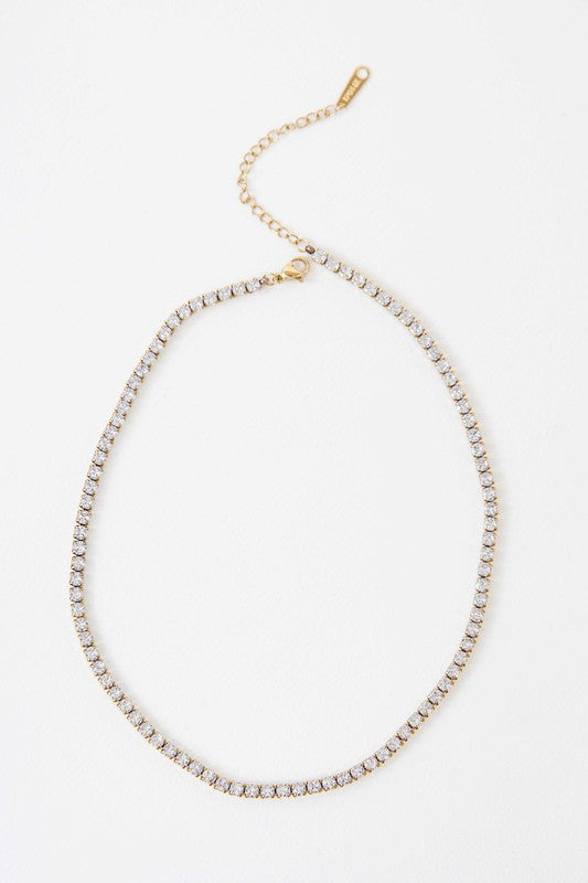 Gold-tone round stone tennis necklace with white crystal stones on a silver background.