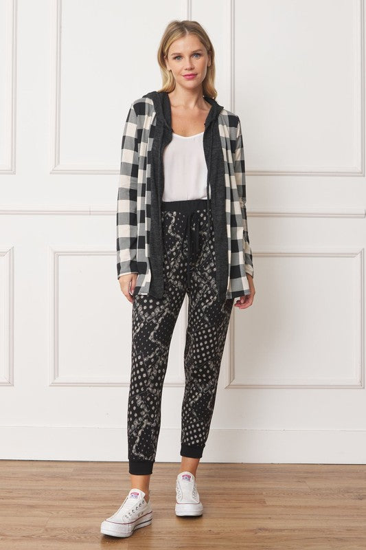 A woman wearing a Buffalo Plaid Hooded Cardigan and patterned pants stands against a white paneled background. Made in the United States.