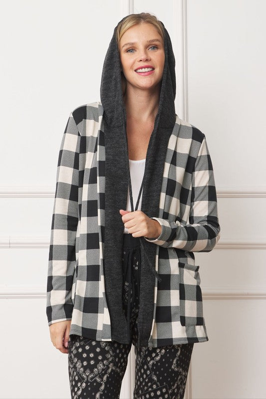 A woman wearing a Buffalo Plaid Hooded Cardigan and patterned pants stands against a white paneled background. Made in the United States.