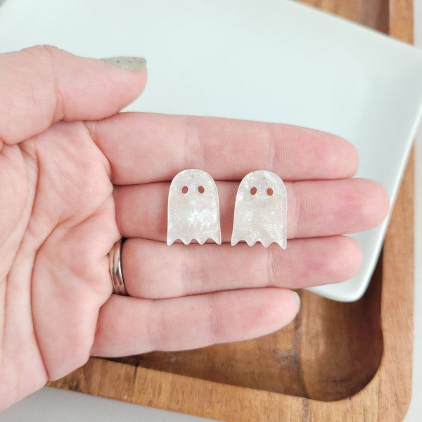 Woman wearing Ghost Studs, smiling and touching her hair.