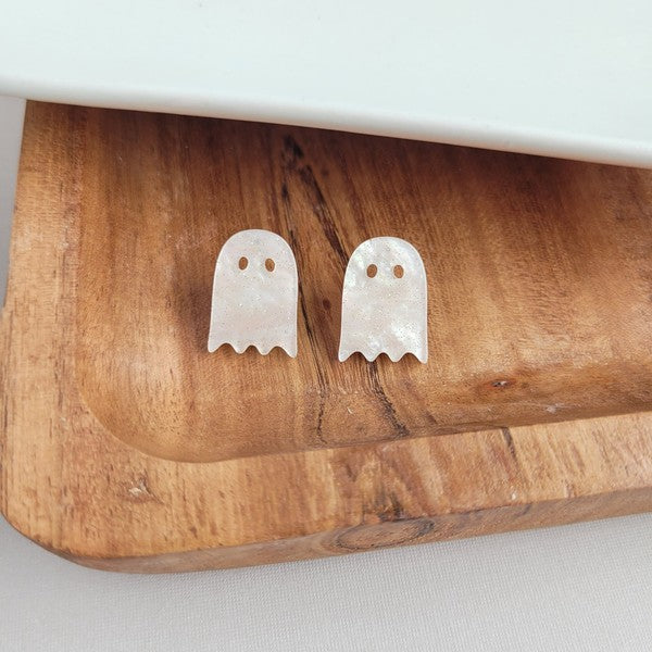 Woman wearing Ghost Studs, smiling and touching her hair.