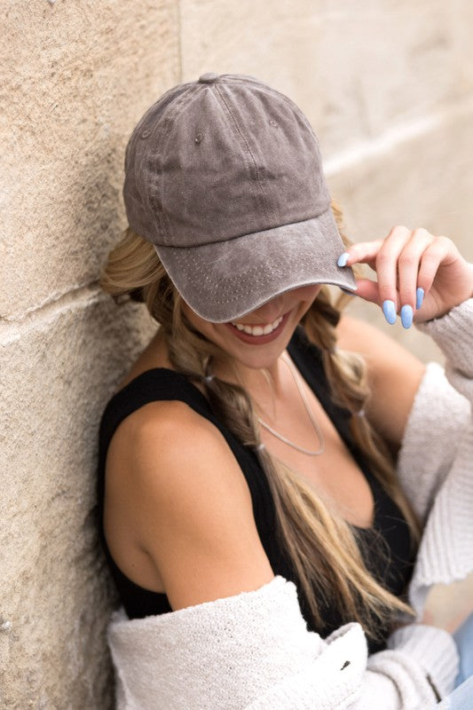 Woman in an Everyday Washed Ball Cap smiling and leaning against a wall.
