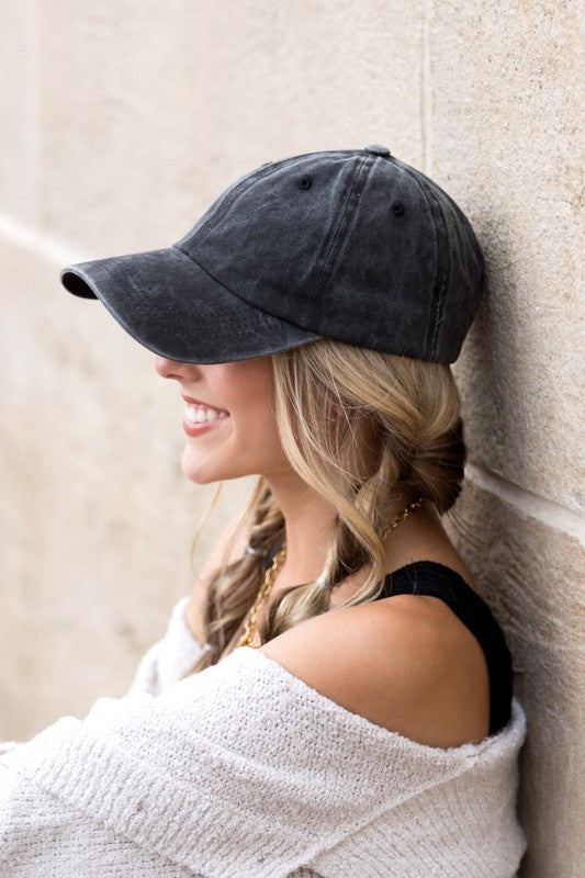 Woman in an Everyday Washed Ball Cap smiling and leaning against a wall.