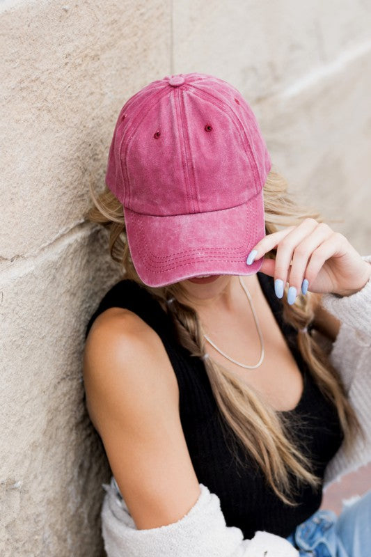 Woman in an Everyday Washed Ball Cap smiling and leaning against a wall.