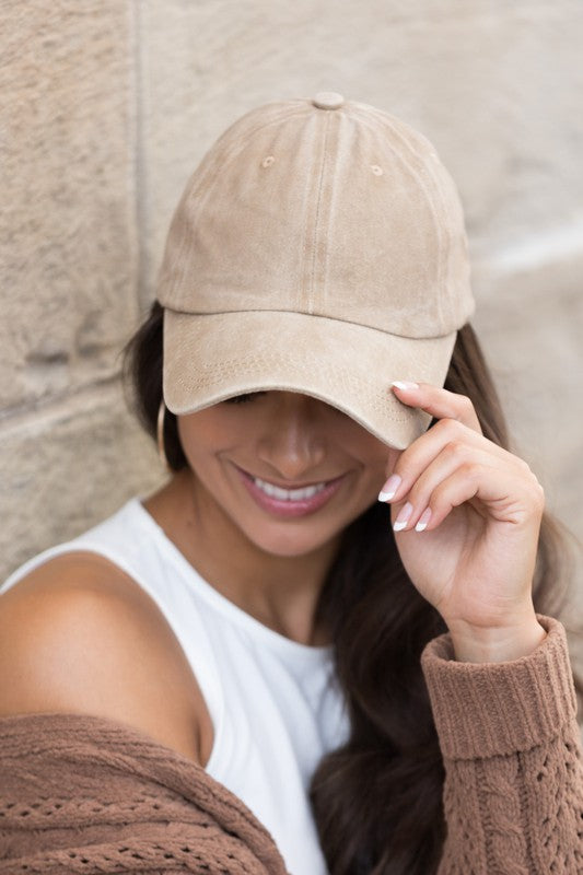 Woman in an Everyday Washed Ball Cap smiling and leaning against a wall.