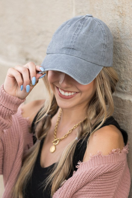 Woman in an Everyday Washed Ball Cap smiling and leaning against a wall.