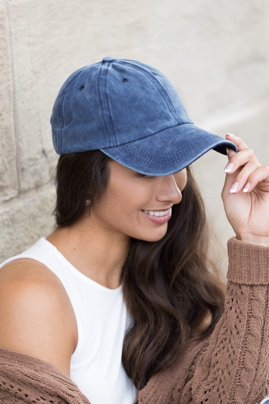 Woman in an Everyday Washed Ball Cap smiling and leaning against a wall.