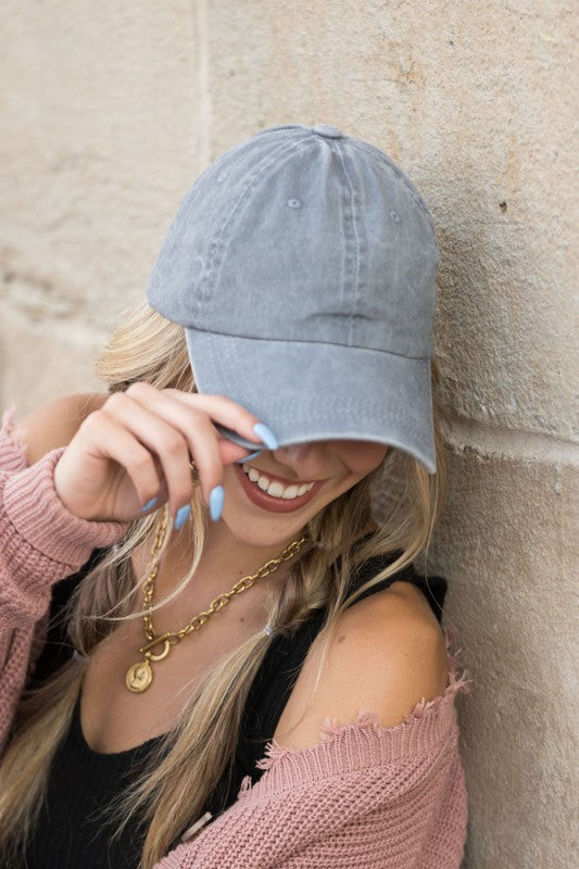 Woman in an Everyday Washed Ball Cap smiling and leaning against a wall.