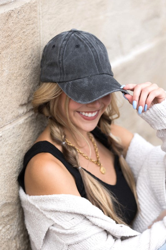 Woman in an Everyday Washed Ball Cap smiling and leaning against a wall.
