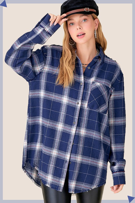 A person with long blonde hair wearing a black cap and an oversized Celine Shirt, which features a blue checkered plaid flannel design, showing a slight smile against a neutral background.