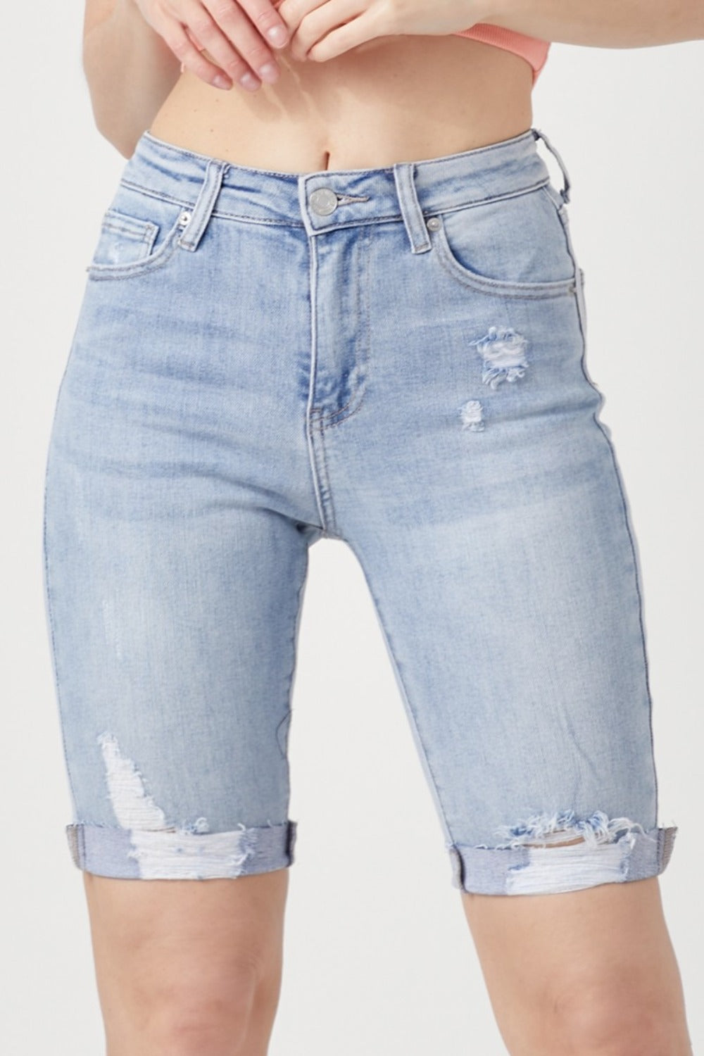 Person wearing RISEN High Rise Distressed Denim Bermuda Shorts with rolled cuffs, showcasing a flattering silhouette against a plain background—giving a trendy twist to classic denim.