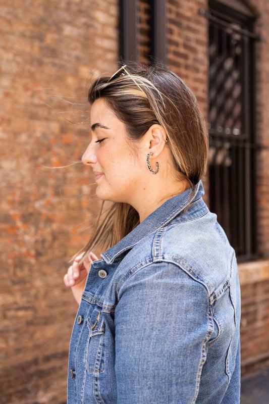 The Camy Hoops - Black Dot are medium-sized hoop earrings featuring a black and white spotted pattern, crafted from lightweight acrylics, elegantly displayed on a white rectangular dish placed on a wooden surface.